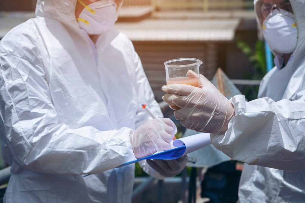 two men in protective gear examining water for pollutants