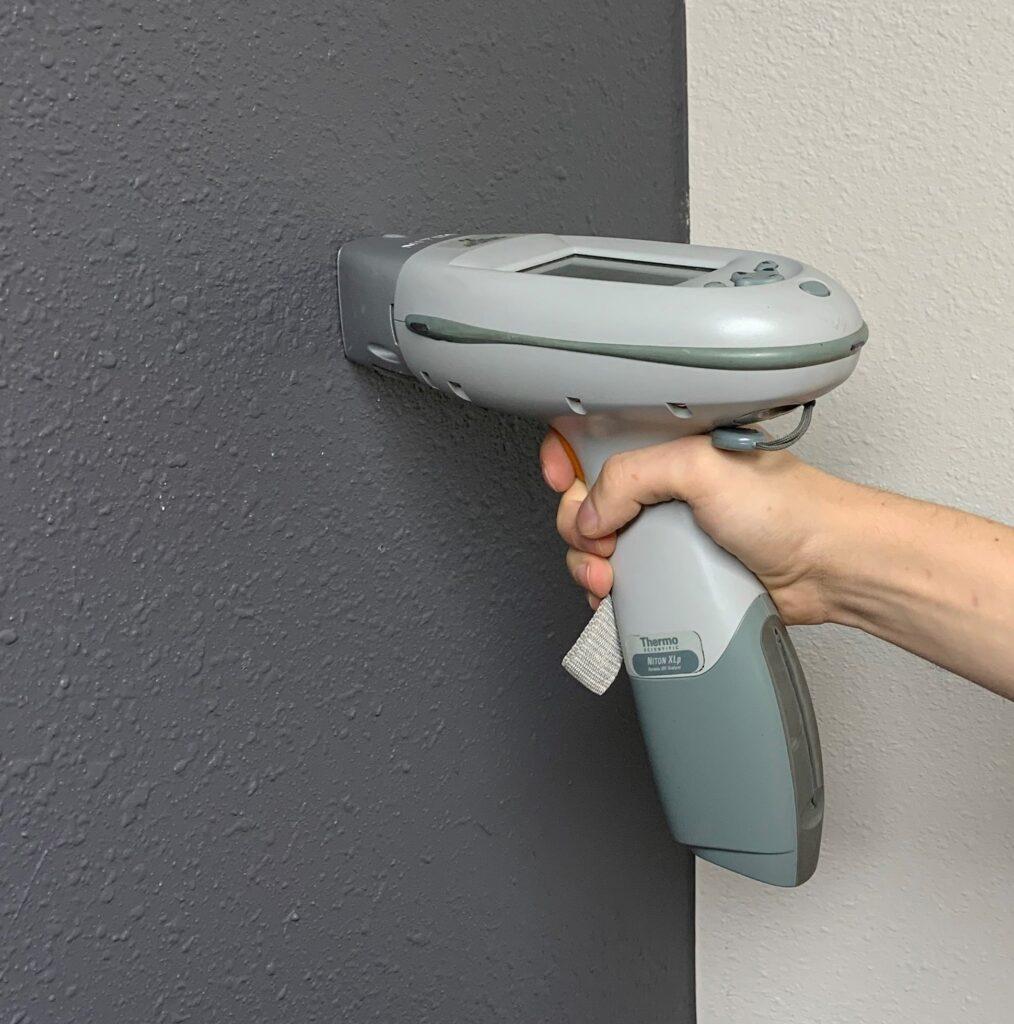 person using an XRF gun to test for lead based paint on their walls