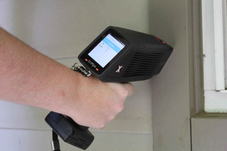 A hand holding a device that measures lead paint levels.