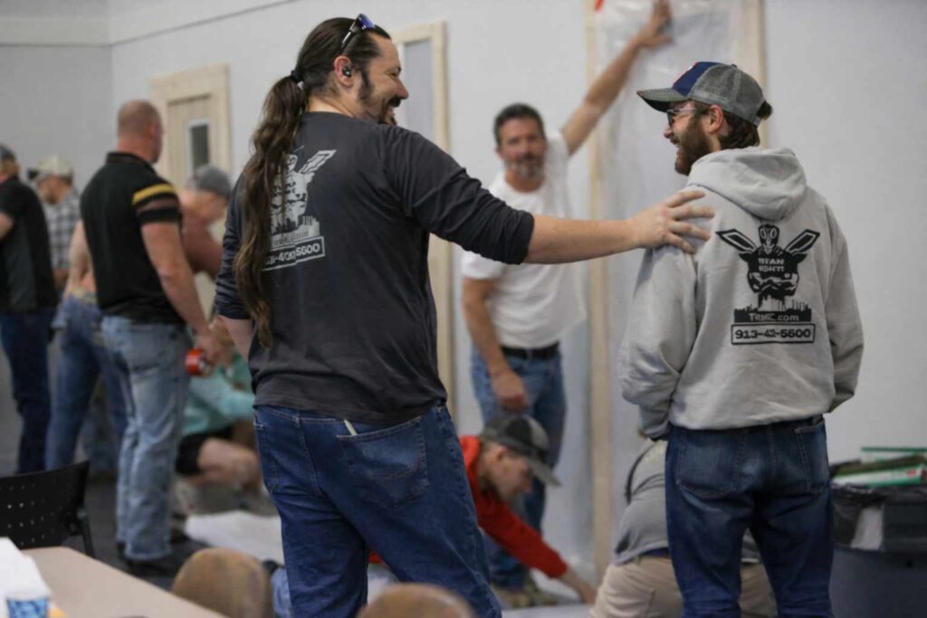 Two men wearing Titan Environmental uniforms share a friendly moment while teaching RRP students.